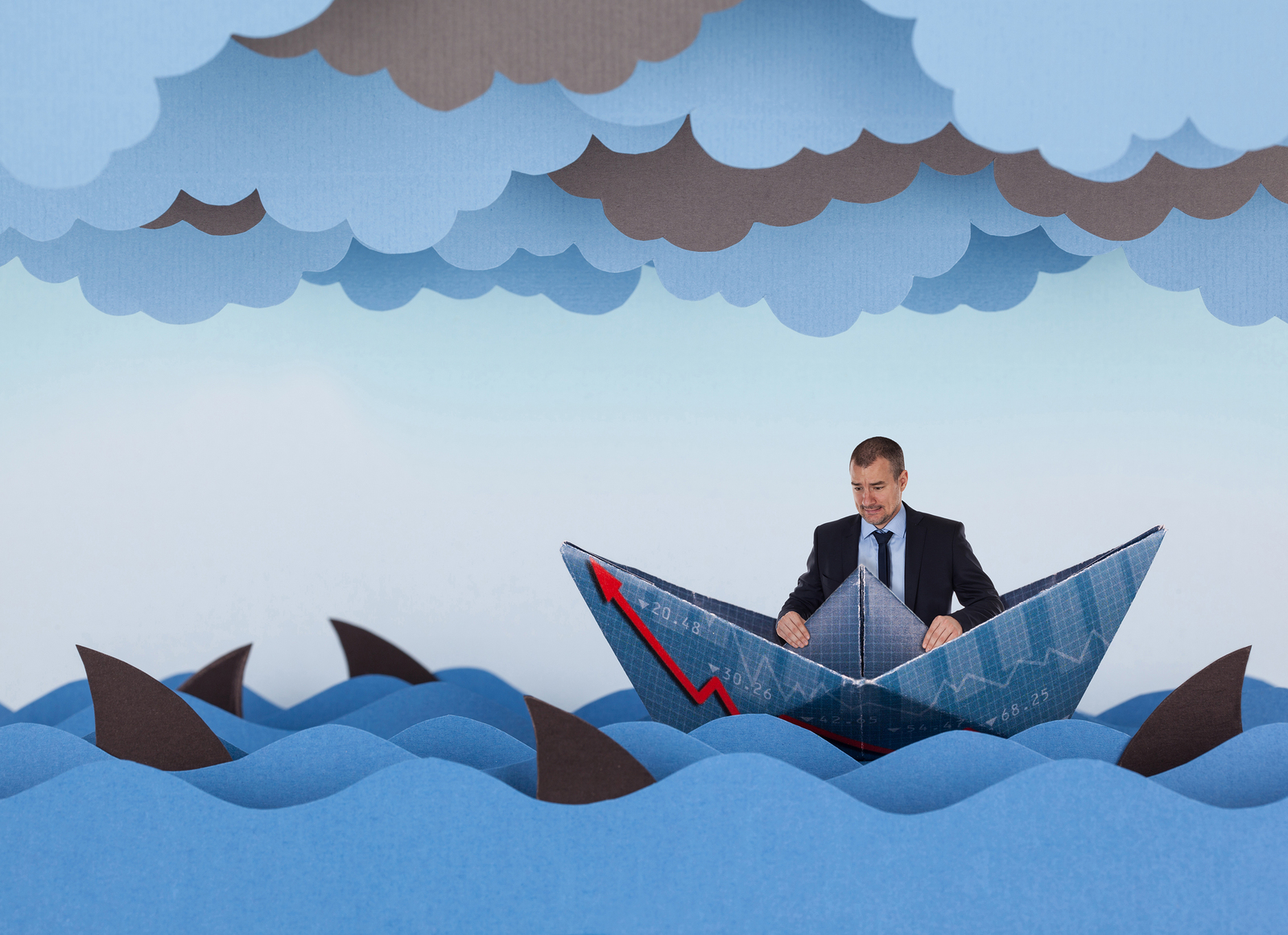 Businessman surrounded by sharks in stormy sea. Competitive business concept. Paper waves clouds boat and 